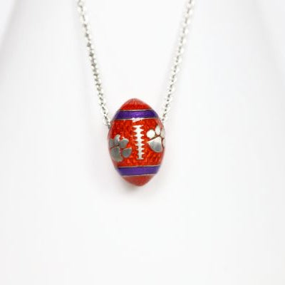 Support the Clemson Tigers with our orange enamel football pendant! Features: Sterling silver Purple and yellow enamel Lobster clasp Officially licensed product Pendant box included football baseball basketball college world series womens mens gift present mothers day fathers day clemson university clemson tigers clemson football team orange and purple paw print