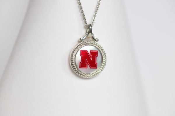 Perfect for any season! Each Mother of Pearl is one-of-a-kind. Features: Sterling silver Mother of pearl with Husker Red enamel inlay Lobster clasp Officially licensed product Pendant box included