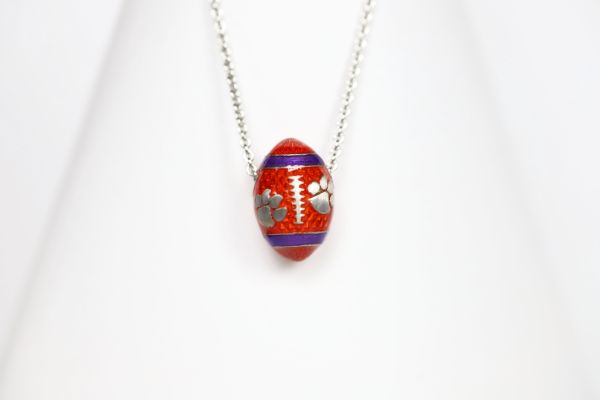 Support the Clemson Tigers with our orange enamel football pendant!   Features:  Sterling silver Purple and yellow enamel Lobster clasp Officially licensed product Pendant box included football baseball basketball college world series womens mens gift present mothers day fathers day clemson university clemson tigers clemson football team orange and purple  paw print 