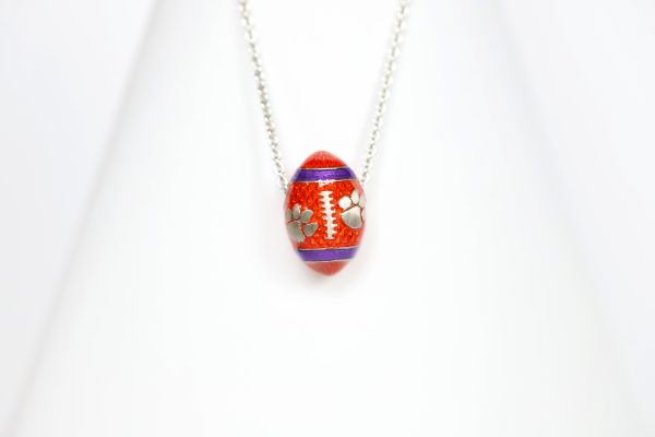 Support the Clemson Tigers with our orange enamel football pendant!   Features:  Sterling silver Purple and yellow enamel Lobster clasp Officially licensed product Pendant box included football baseball basketball college world series womens mens gift present mothers day fathers day clemson university clemson tigers clemson football team orange and purple  paw print `