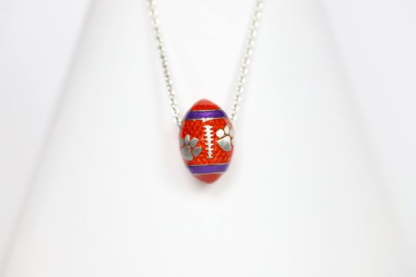 Support the Clemson Tigers with our orange enamel football pendant!   Features:  Sterling silver Purple and yellow enamel Lobster clasp Officially licensed product Pendant box included football baseball basketball college world series womens mens gift present mothers day fathers day clemson university clemson tigers clemson football team orange and purple  paw print 